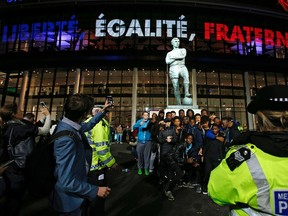 A police officer watches as a man takes photos of a group supporters before the international soccer match between England and France at Wembley Stadium in London, Tuesday, Nov. 17, 2015. (AP Photo/Alastair Grant)