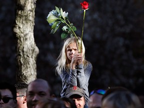 FILE - In this Monday, Nov. 16, 2015, file photo, Neeley, 8, of Virginia, sits on her father's shoulders during a moment of silence that was part of a tribute and ceremony remembering victims of this weekend's Paris attacks at the 9/11 Memorial and Survivor Tree in New York. The deadly attacks in France left schools and parents around the world grappling with what to say to children, and how to say it. From country to country, the topic was tackled in different ways. (AP Photo/Kathy Willens)