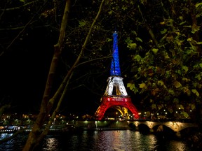 The illuminated Eiffel Tower in the French national colors red, white and blue in honor of the victims of the terrorist attacks last Friday, and Seine river are seen in Paris, Tuesday, Nov. 17, 2015. (AP Photo/Peter Dejong)