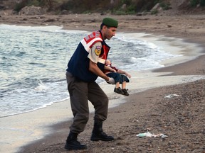 In this Sept. 2, 2015 file photo, a paramilitary police officer carries the lifeless body of Aylan Kurdi, 3, after a number of migrants died when boats carrying them to the Greek island of Kos capsized near the Turkish resort of Bodrum. This incident sparked international outrage and caused many countries to pledge to help refugees. (AP Photo/DHA, File)