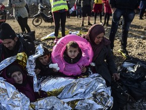 A Syrian family waits after arriving on the Greek island of Lesbos along with other migrants and refugees, on November 17, 2015, after crossing the Aegean Sea from Turkey. (AFP PHOTO/BULENT KILIC)
