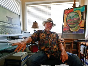 This July 16, 2014 file photo, artist Michael Gross sits in his studio between one of his paintings and one of his photos on his computer screen in Oceanside, Calif. (AP Photo/Lenny Ignelzi, File)