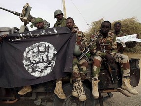 Nigerien soldiers hold up a Boko Haram flag that they had seized in the recently retaken town of Damasak, Nigeria, March 18, 2015. Chadian and Nigerien soldiers had taken the town from Boko Haram militants earlier in the week.    REUTERS/Emmanuel Braun
