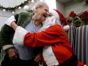 Stephanie Sprysak, 104, gets a kiss from Santa Claus at McConnell Place North, 9113 - 144 Ave., in Edmonton Alta., on Tuesday Dec. 23, 2014. Santa and a group of Edmontonians 'adopted' the facility's 36 residents, delivering present for each senior, as well as singing Christmas Carols. David Bloom/Edmonton Sun