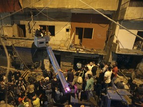 Residents and Lebanese army members use a crane to inspect a damaged area caused by two explosions in Beirut's southern suburbs, Lebanon November 12, 2015. (REUTERS/Khalil Hassan)