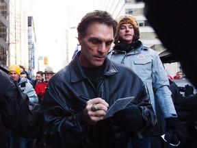 Former CFL and NFL quarterback Doug Flutie signs an autograph for a fan as takes part in the fan march before the Toronto Argonauts take on the Calgary Stampeders for the 100th Grey Cup in Toronto on Sunday, Nov. 25, 2012. (THE CANADIAN PRESS/Michelle Siu)