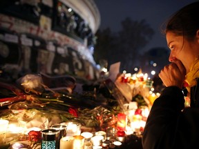 A woman weeps as she kneels near bouquets of flowers and burning candles at the Place de la Republique in Paris on Nov. 16 as people continue to pay tribute to the victims of the series of deadly attacks in the French capital on Nov. 13. (Christian Hartmann/Reuters)