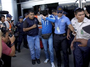 Policemen escort one of six Syrian men detained at Toncontin international airport in Tegucigalpa, Honduras, November 18, 2015. Honduran authorities have detained Syrian nationals who were trying to reach the United States using stolen Greek passports, but there are no signs of any links to last week's attacks in Paris, police said. The passports had been doctored to replace the photographs with those of the Syrians, police said. REUTERS/Stringer