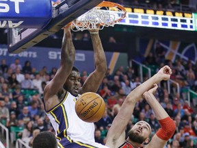 Utah Jazz forward Derrick Favors throws down a dunk over Raptors’ Jonas Valanciunas (right) and Kyle Lowry during Wednesday night’s game in Salt Lake City. The Raptors lost 93-89. (AP)