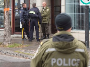 RCMP and Surete du Quebec police officers stand outside the offices of Rizzuto family lawyer Loris Cavaliere during a raid Thursday, November 19, 2015 in Montreal. Three police forces arrested 40 people including alleged Mafia boss Leonardo Rizzuto on drug trafficking charges. THE CANADIAN PRESS/Ryan Remiorz