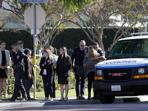 Unidentified police officers react as Los Angeles County Coroner transports the body of Downey police Officer Ricardo "Ricky" Galvez in Downey, Calif., on Thursday, Nov. 19, 2015. Galvez was in plainclothes and sitting in the driver's seat of his personal car when two men ran up and opened fire late Wednesday. Los Angeles County authorities say they've made an arrest and that more could be imminent in the fatal shooting of an officer near his police department headquarters. (AP Photo/Nick Ut)