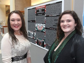 Queen's University students Claire Stacey, left, and Kacey Dool stand in front of their project on residential schools in Kingston, Ont. on Thursday, Nov. 19, 2015. The assignment called for the students to investigate how religion affected childhood. Michael Lea/The Whig-Standard/Postmedia Network