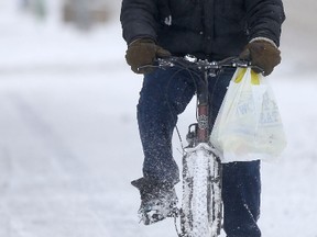 A storm, with snow, and blowing snow, arrived in Winnipeg today.  This cyclist is riding on the sidewalk, on Portage 
Avenue.  Thursday, November 19, 2015.   Sun/Postmedia Network