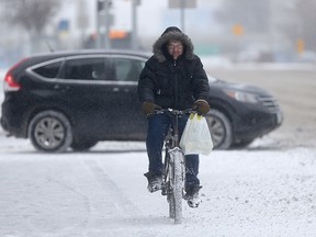 A storm, with snow, and blowing snow, arrived in Winnipeg today.  This cyclist is riding on the sidewalk, on Portage 
Avenue.  Thursday, November 19, 2015.   Sun/Postmedia Network