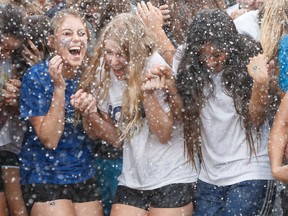 Students at St. Francis Xavier High School are hosed down for the ALS Ice Bucket Challenge by water truck in Edmonton, Alta., on Thursday, Sept. 18, 2014. Canadian universities will share in a $15 million research fund announced by ALS Societies and the ALS Canada Research Program. Ian Kucerak/Edmonton Sun/Postmedia Network