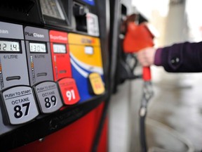 A motorist reaches for the pump at a gas station, in Toronto, on Feburary 24, 2011. Lower gasoline prices continued to weigh against a rise in the cost of food in October as the consumer price index rose 1.0% compared with a year ago. (THE CANADIAN PRESS/Patrick Dell)
