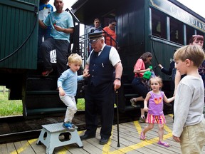 Conductor Bill Tront helps a young passenger off the train at Fort Edmonton Park in Edmonton, Alta., on Monday, May 20, 2013. Codie McLachlan/Edmonton Sun