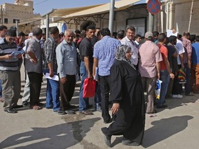 Syrian refugees gather outside their embassy waiting to apply for passports or to renew their old passports, in Amman, Jordan.