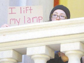 Kate Elliott, of Cumberland, R.I., displays a placard during a rally Thursday at the statehouse in Providence, demanding that Syrian refugees be allowed to enter Rhode Island and the United States following the terror attacks in Paris. (Steven Senne/AP Photo)