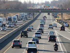 People line the Old Victoria Road overpass Friday as the hearse carrying John Gallagher is driven along Highway 401  through London. (CRAIG GLOVER, The London Free Press)