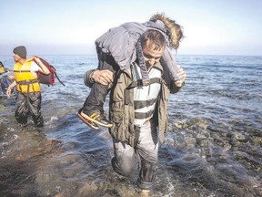 A man disembarks from a dinghy carrying a child after crossing the Aegean sea with other refugees to the Greek island of Lesbos. (Santi Palacios/The Associated Press)