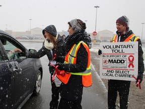 Lambton College student Madison Scott collects a donation from a driver while peers Tiffany Male and Jon Martinez look on at Sarnia's SmartCentre parking lot Saturday November 21, 2015 in Sarnia, Ont. Volunteers with Mothers Against Drunk Driving (MADD) Sarnia-Lambton fanned out across the community to stage their annual voluntary toll campaign to spread awareness about the importance of sober driving during the holiday season. Barbara Simpson/Sarnia Observer/Postmedia Network
