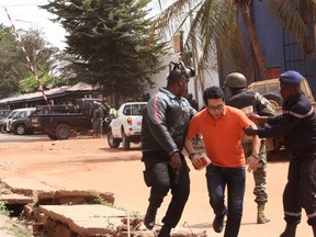 In this Friday, Nov. 20, 2015 file photo, Mali troopers assist a hostage to leave the Radisson Blu hotel to safety after gunmen attacked the hotel, in Bamako, Mali. The al-Qaida-claimed attack on a Mali hotel may have been partly aimed at asserting the global terror network’s relevance as it faces an unprecedented challenge from the Islamic State group for leadership of the global jihadi movement. While the two groups share similar goals they have been bitterly divided over strategy and leadership, and have come to blows in Syria. (AP Photo/Harouna Traore, File)
