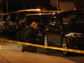 An Ottawa Police investigator examines evidence found on Bradley Ave. in Vanier following a shooting that sent a 20-year-old man to hospital with two gunshot wounds. Corey Larocque, Ottawa Sun