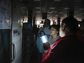 An electronics store employee uses a lamp to show items to potential customers after a power failure, in Simferopol, Crimea, on Nov. 22, 2015. Russia's Energy Ministry says nearly 2 million people on the Crimean Peninsula are without electricity after two transmission towers in Ukraine were damaged by explosions. (AP Photo/Alexander Polegenko)