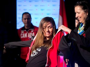 Tricia Smith presents Canadian snowboard team member Maelle Ricker of West Vancouver with her team jacket during the team announcement in Vancouver on Jan. 3, 2014.  THE CANADIAN PRESS/Jonathan Hayward