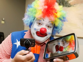 Clown Shane Federman holds his dash cam recorder and the mirror which was torn off his SUV during a violent incident involving a stranger on the street. (MICHAEL PEAKE, Toronto Sun)