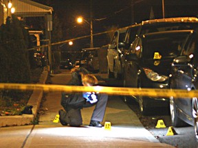 An Ottawa Police investigator examines evidence found on Bradley Ave. in Vanier following a shooting that sent a 20-year-old man to hospital with two gunshot wounds on Saturday, Nov. 21, 2015. Police say it was a gang-related shooting. It's the city's 40th of the year.
Corey Larocque/Ottawa Sun