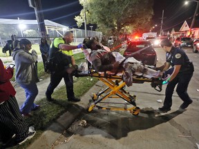 Officials remove a man from the scene following a shooting in New Orleans' 9th Ward on Sunday, Nov. 22, 2015. Police spokesman Tyler Gamble says police were on their way to break up a big crowd when gunfire erupted at Bunny Friend Park. (Michael DeMocker/NOLA.com The Times-Picayune via AP)