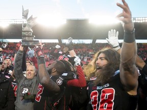 Ottawa Redblacks head coach Rick Campbell holds up the East Division trophy as players celebrate following their win over the Hamilton Tiger-Cats in the CFL East final Sunday, November 22, 2015 in Ottawa. The Redblacks will advance to the Grey Cup after defeating the Hamilton Tiger-Cats. THE CANADIAN PRESS/Adrian Wyld