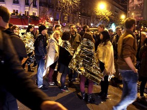 People warm up under protective thermal blankets as they gather on a street near the Bataclan concert hall following fatal attacks in Paris, France, Nov. 14, 2015. REUTERS/Philippe Wojazer