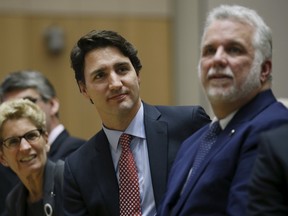 Prime Minister Justin Trudeau (C) sits with Ontario Premier Kathleen Wynne (L) and Quebec Premier Philippe Couillard while listening to a question from a student during the First Ministers' meeting in Ottawa, Canada November 23, 2015. REUTERS/Chris Wattie