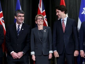 Nova Scotia Premier Stephen McNeil, left, bends his knees to match the height of Ontario Premier Kathleen Wynne, centre, as Prime Minister Justin Trudeau looks on during a group photo at the First Ministers' meeting in Ottawa, November 23, 2015. (REUTERS/Chris Wattie)