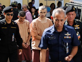 Police officers escort suspects in the Aug. 17 blast at Erawan Shrine, Bilal Mohammad, centre front, and Mieraili Yusufu, rear centre, as they arrive at a military court in Bangkok, Thailand, Tuesday, Nov. 24, 2015. The military court has indicted two men police say carried out the deadly August bombing at the shrine that left 20 people dead and more than 120 injured. (AP Photo/Sakchai Lalit)