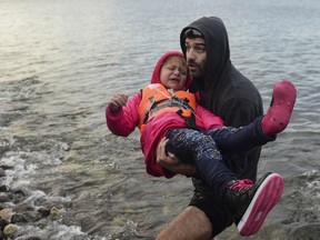 A man carries a girl upon their arrival on the Greek island of Lesbos after crossing the Aegean Sea from Turkey with other migrants and refugees November 24, 2015. (AFP PHOTO / BULENT KILIC)