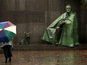 A woman stands before a statue of U.S. President Franklin Delano Roosevelt and his dog Fala as she tours the FDR Memorial on a rainy morning in Washington, November 19, 2015. REUTERS/Kevin Lamarque