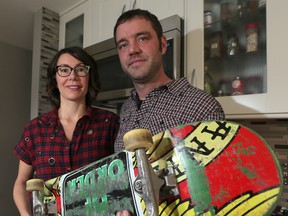 Dwayne Mazereeuw and his wife Elisa Kasha hold up a skateboard at their SE Calgary, Alta. home on Monday November 23, 2015.The two were on-board the boat that capsized and sunk near Tofino, BC last month and want to repay the native community who rescued them by designing and raising money for a skateboard park on their land. Stuart Dryden/Calgary Sun/Postmedia Network