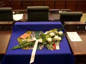 A flag and flowers are draped over the desk of MLA Manmeet Bhullar at the Alberta Legislature chambers in Edmonton Alta, on Tuesday November 24, 2015. Bhullar, 35, was killed in a car accident on Monday afternoon while driving from Calgary to Edmonton. THE CANADIAN PRESS/Jason Franson