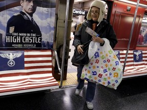 Passengers board a 42nd Street Shuttle subway train, wrapped with advertising for the Amazon series "The Man in the High Castle" in the Manhattan borough of New York, Nov. 24, 2015.   REUTERS/Brendan McDermid