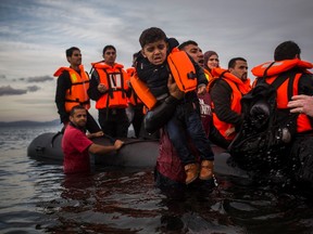 Volunteers assist refugees from a dinghy after they crossed a part of the Aegean sea from Turkey to the northeastern Greek island of Lesbos, on Tuesday, Nov. 24, 2015. (AP Photo/Santi Palacios)