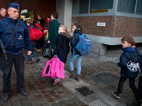 Children pass a police officer as they arrive for school in the center of Brussels on Wednesday, Nov. 25, 2015.  (AP Photo/Virginia Mayo)