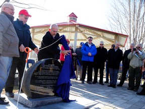 EMILY MOUNTNEY-LESSARD/THE INTELLIGENCER
Belleville Mayor Taso Christopher helps unveil a CN Train Monument Committee stone during an unveiling and gazebo ribbon cutting on Wednesday. Also shown are committee chairman David Simpson (centre) and member John Carson.