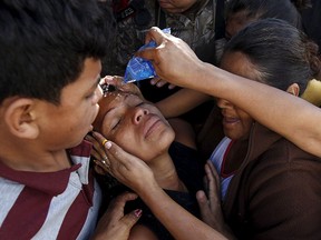 Residents help a relative (C) of a slain victim at a crime scene where seven men were killed, in Tegucigalpa, Honduras, Nov. 25, 2015.  REUTERS/Jorge Cabrera