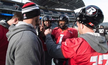 Ottawa Redblacks quarterback Henry Burris, centre, fist bumps with the teams other quarterbacks during a practice session in Winnipeg, Man., Wednesday, Nov. 25, 2015. The Redblacks will play the Edmonton Eskimos in the 103rd Grey Cup on Sunday. THE CANADIAN PRESS/Jonathan Hayward