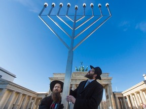 Rabbis Schmuel Segal (L) and Yehuda Teichtal of the Orthodox Jewish Chabad Lubavitch community bless a menorah after erecting it in front of the Brandenburg Gate in Berlin, Dec. 7, 2012. REUTERS/Thomas Peter