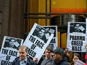 In this Thursday, Oct. 1, 2015, file photo, activists hold signs containing the image of Turing Pharmaceuticals CEO Martin Shkreli in front the building that houses Turing's offices, in New York, during a protest highlighting pharmaceutical drug pricing.  (AP Photo/Craig Ruttle, File)